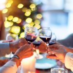 A group of people clinking their wine glasses over a table of food